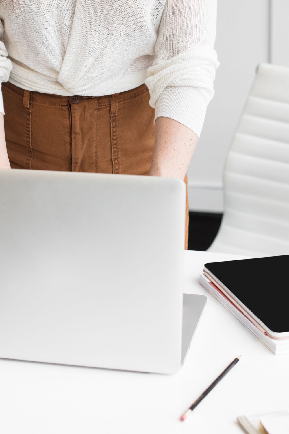 A woman stands behind her desk and laptop, segmenting her email list.